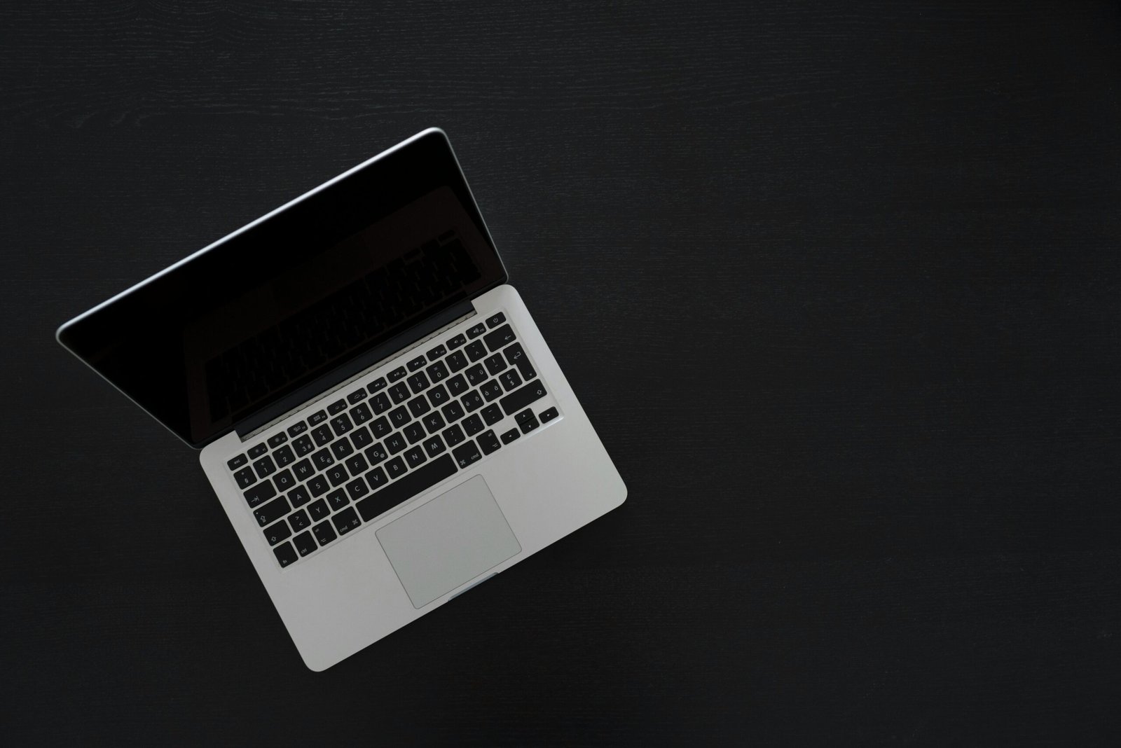 Overhead view of a MacBook laptop on a dark desk, showcasing modern technology and minimalism.