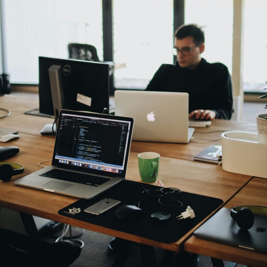 A web developer working on code in a modern office setting with multiple devices.